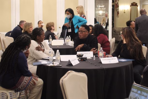 Small groups of attendees talking around round tables at a conference workshop